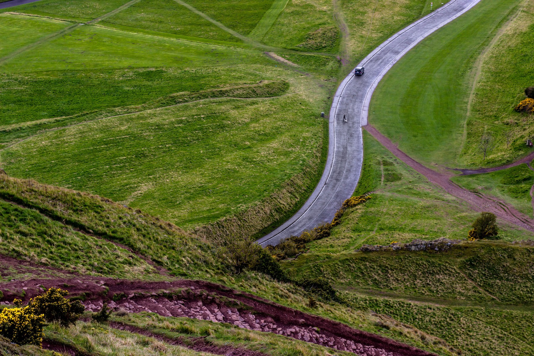 A car travelling along a winding road through green hills